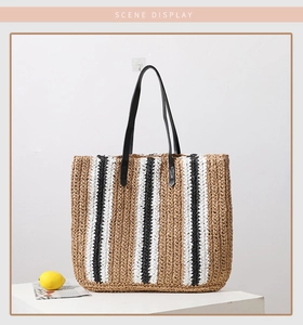 Detailed close-up of handmade striped straw tote bag with black PU handles on white background