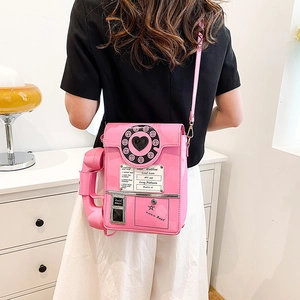 Detail of pink retro telephone shaped crossbody bag with dial and glossy patent leather finish