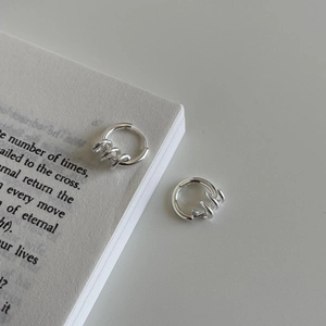 Minimalist 925 sterling silver triple hoop earrings with a spiral twist design on a book