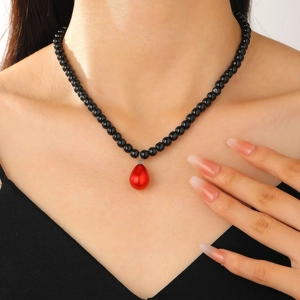 Collar vintage de perlas negras brillantes con gran colgante de gota roja en una modelo