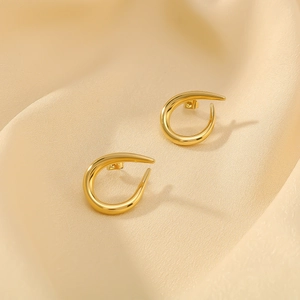 Polished 18k gold plated stainless steel C-shaped twist earrings on beige silk fabric