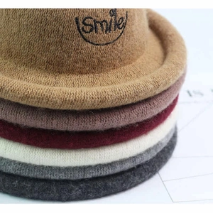 Close-up of stacked knitted wool hats with Smile embroidery in multiple autumn colors