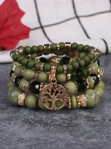 Detail eines böhmischen Lagenarmbands mit grünen Perlen und goldenem Lebensbaum-Anhänger