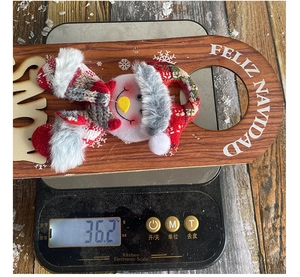Detailed view of Feliz Navidad snowman wooden door hanger on a digital scale for weight measurement