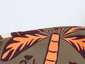 Close-up of woven fabric with orange palm tree print on a brown background set