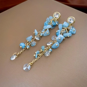 Boucles d'oreilles dorées avec cristaux bleu clair et longs glands sur velours