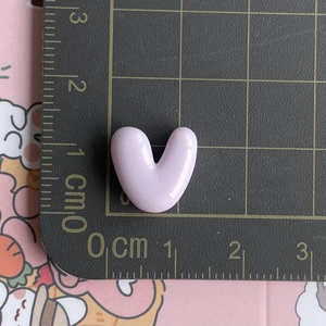 Macro view of a 1cm light purple resin heart accessory on a black measuring mat