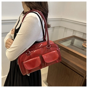 Detail view of red glossy patent leather shoulder bag with dual front flap pockets