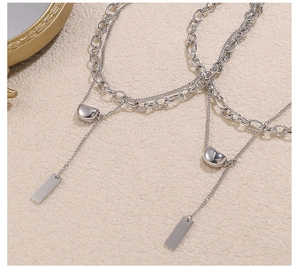 Close-up of double layer silver stainless steel necklace with geometric lucky bean pendants