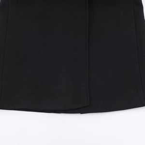 Close-up of black blended fabric texture and hem detail on a long casual coat