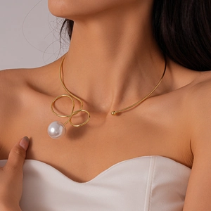 Detailed view of a gold twisted wire choker necklace with a large round white pearl pendant