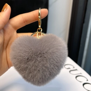 Detailed macro of a fluffy grey heart-shaped plush keychain with gold lobster clasp