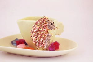 Close-up of pink and white crystal hedgehog keychain with shiny gold plating detail