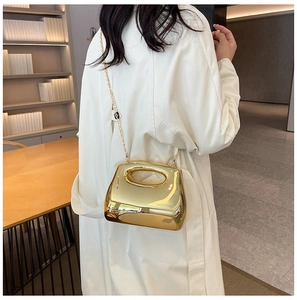 Close-up of golden acrylic evening bag with mirror finish and stylish chain strap