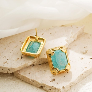 Close-up of 18K gold vintage earrings with rectangle green stones on stone