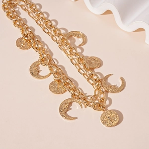Detail of gold double-layer necklace with sun and moon embossed coin pendants