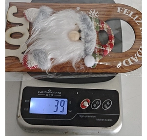 Close-up of wooden Christmas Joy door hanger showing product weight of 39g on a scale