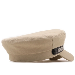 Detail of khaki sailor cap featuring a black strap with rows of shimmering rhinestones