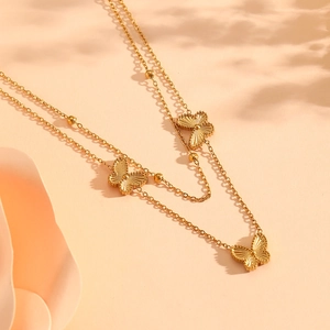 Collier double couche doré élégant avec pendentifs papillons et détails de perles