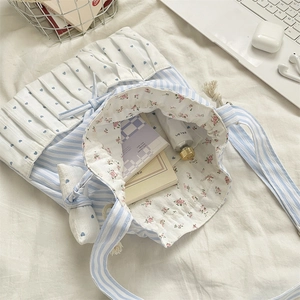 Close-up of blue striped tote bag featuring heart ruffles and floral lining details
