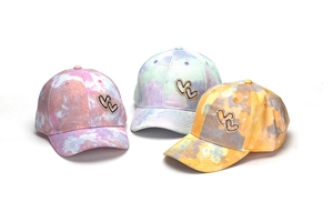 Detail view of three colorful tie-dye baseball caps for kids with rhinestone heart patches