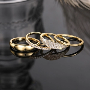 Macro shot of gold stacked rings set with shimmering zircon stones on dark surface