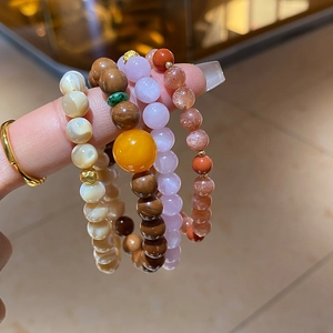 Detail view of multi-layered beaded bracelets with shell, stone and crystal textures
