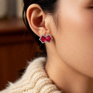 Close-up of a sparkling bow-shaped earring with red gemstone and micro-pave crystals