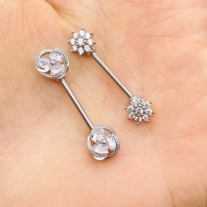 Close-up of surgical steel nipple rings featuring cubic zirconia flower ends on palms