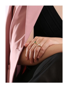 Close-up of gold open ring with heart and green gems on model for an elegant style
