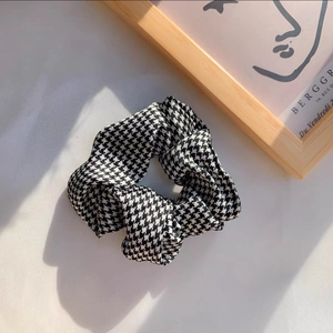 Detail of elegant black and white houndstooth hair scrunchie with soft fabric texture