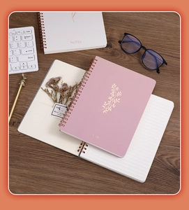 Close-up of A5 spiral notebook with pink gold foil leaf design and lined inner pages
