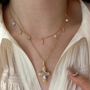 Detail of layered gold Vatican cross pendant necklace with teardrop and zircon accents