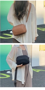 Detail of lychee pattern leather crossbody bag with dual zippers and wide fabric strap