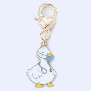 Detail of cartoon doctor duck keychain with blue mask and gold heart-shaped clasp