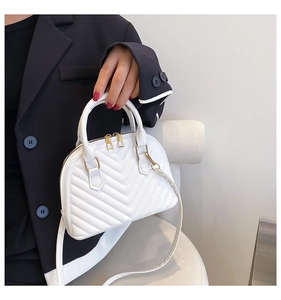 Detailed view of a white quilted shell bag featuring gold zippers and stitching details