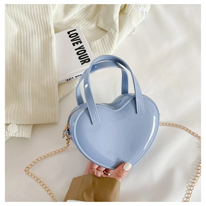 Detail of light blue heart-shaped patent leather mini bag with golden chain strap