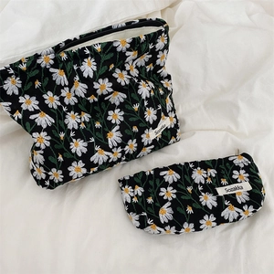 Detailed view of two daisy embroidered fabric pouches in large and small sizes