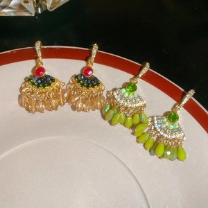 Orecchini vintage a ventaglio con nappe e perle di cristallo su un piatto in ceramica