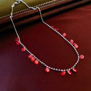 Détail du collier à perles argentées avec pendentifs en zircon rouge sur cuir chic