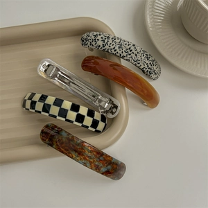 Elegant acetate french hair barrettes in marble and checkered patterns on a tray
