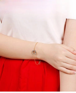 Detail eines goldenen Smiley-Armbands mit funkelnden Zirkoniasteinen am Handgelenk
