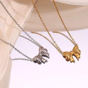 Detailed view of polished ribbon bow pendants in gold and silver finishes on white silk