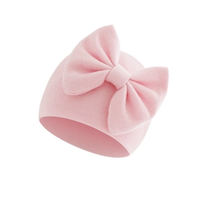Detail of pink knitted baby hat featuring a large bow and soft ribbed texture
