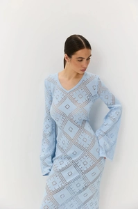 Dettaglio dell'abito in maglia azzurro con scollo a V e motivi geometrici traforati