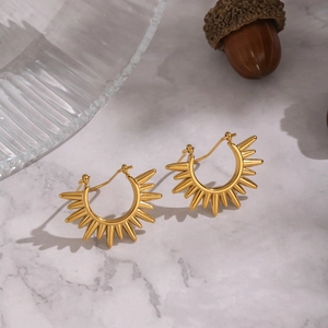 Golden sunburst hoop earrings with radiant spikes on a luxury marble surface