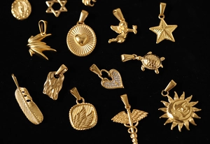 Detailed close-up of various vintage gold-plated titanium pendants on black velvet background