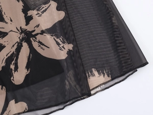 Detailed close-up of beige floral print on black mesh fabric with neat hem stitching