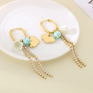 Detailed view of heart-shaped gold earrings with pearl tassels and rhinestone fringe