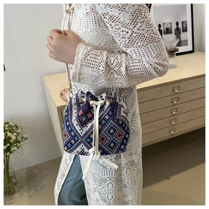 Ethnic style bucket bag with colorful patterns and drawstring closure shown on model